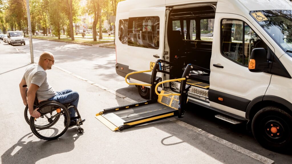 Ein Mann im Rollstuhl fährt zum Lift eines Krankentransportaxis